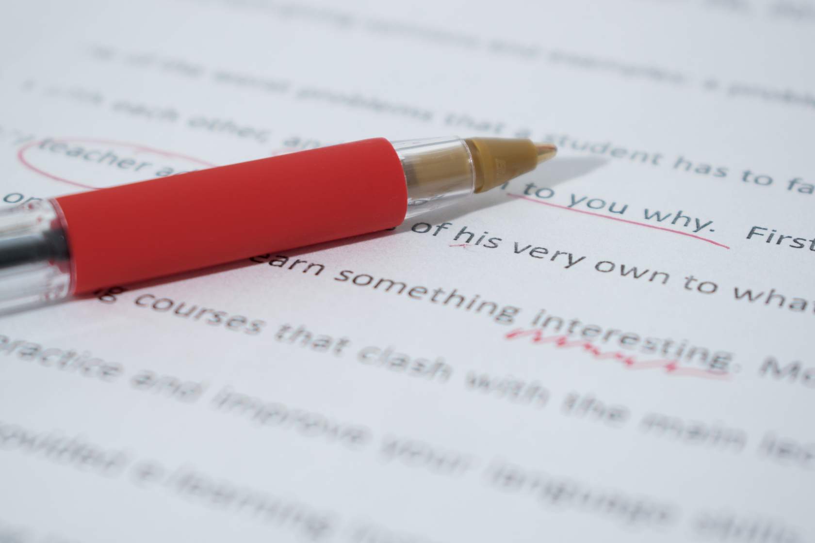 Close-up of a pen laying on paper with writing and editing marks