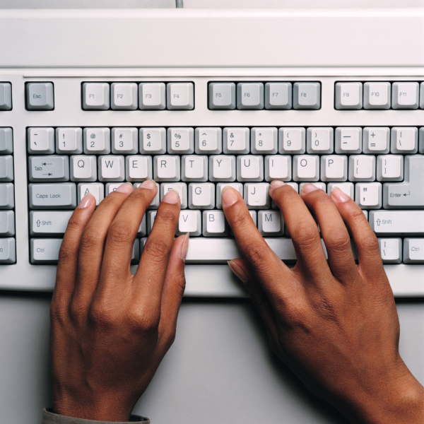 computer keyboard with two hands placed over the keys