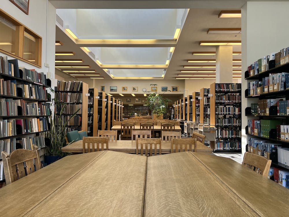 light-filled space surrounded by book, LP stacks with large wood tables and chairs down the center