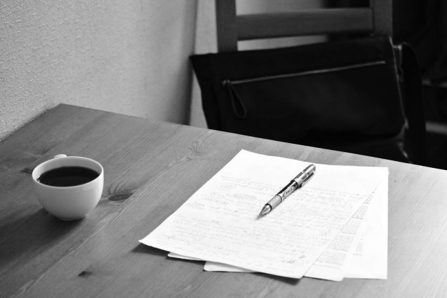 paper, pen, and coffee mug on a desk.