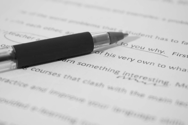 pen laying on paper with text and proofreading marks