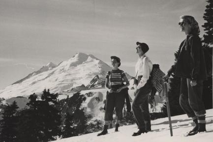Black and white photo of 3 women with backpacks on snow covered mountain top