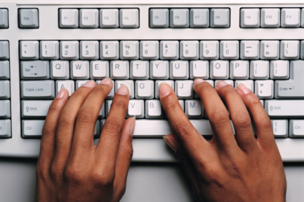 computer keyboard with two hands placed over the keys