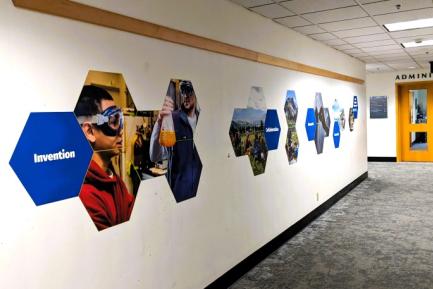 Hallway leading to the new Kitto Graduate Student Hub with images of current and former WWU students engaged in research and graduate work displayed on the hallway wall alongside words such as “Invention” and “Collaboration.”