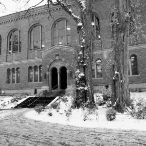 Exterior view of Wilson Library building featuring the north entrance with some snow on the ground and in the trees in front of the building.