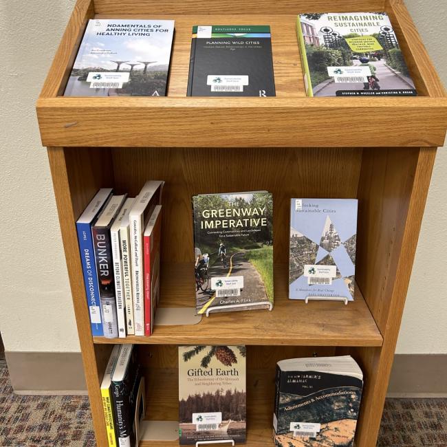 small bookshelf with a collection of books, one clearly titled "The Greenway Imperative"