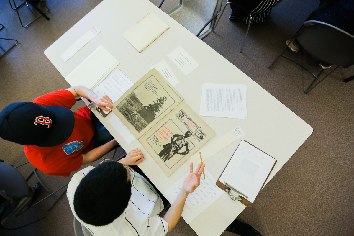 Two students looking at a historical newspaper at the archives.